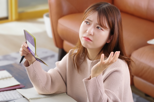 通帳を見て悩む女性